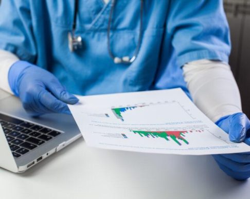Doctor,Wearing,Protective,Gloves,Analyzing,Covid-19,Info,Data,sitting,At,Office